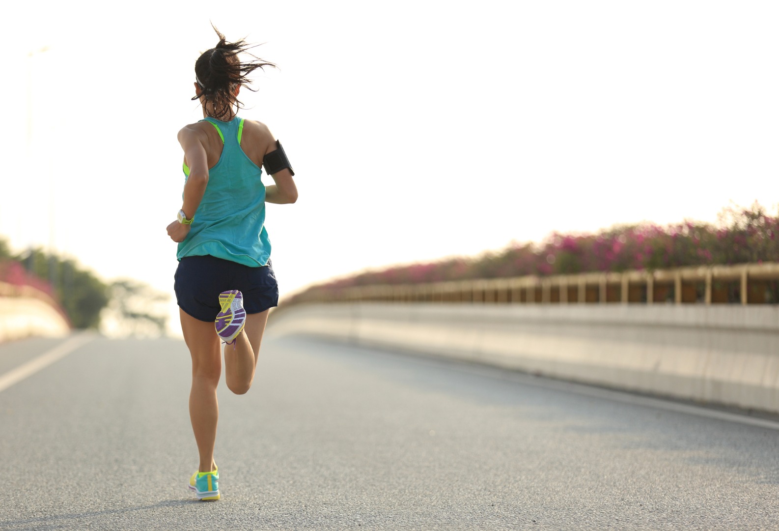 young woman runner running on city bridge road